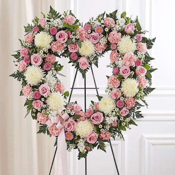 Heart-shaped floral wreath with pink and white flowers on a stand