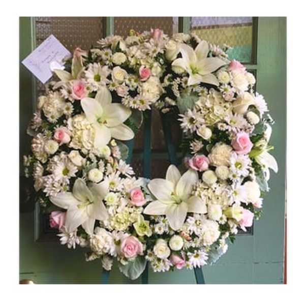 Large white floral wreath with pink roses and lilies