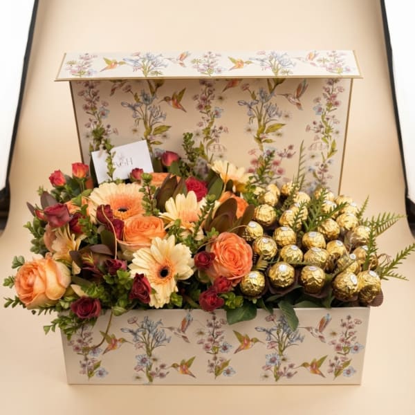 Flower gift box with peach roses, cream daisies, and gold-wrapped chocolates