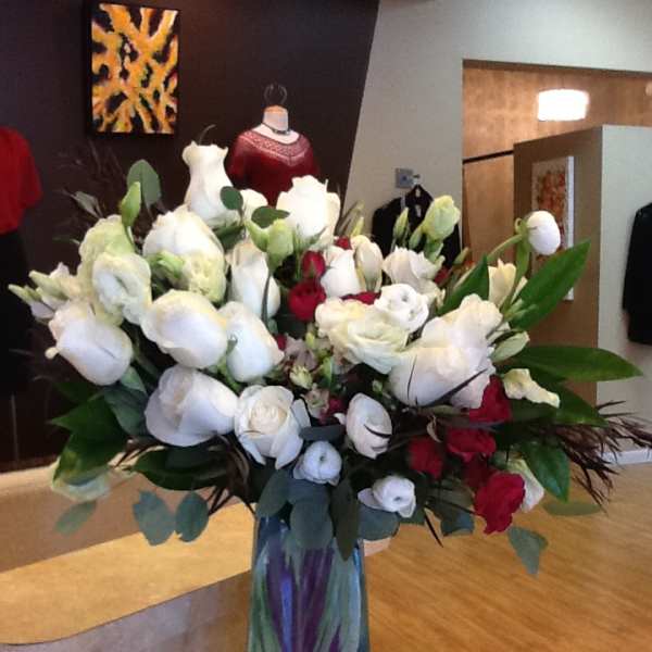 Large bouquet of white and red flowers in a tall glass vase