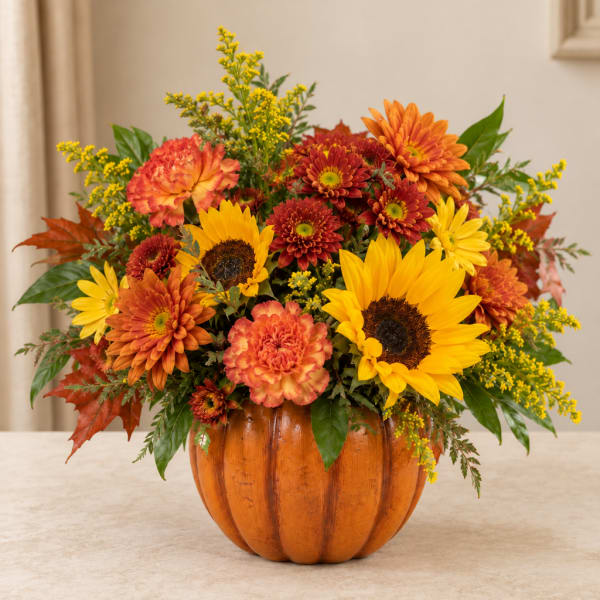 Autumn flower arrangement in a pumpkin-shaped container with sunflowers and mums