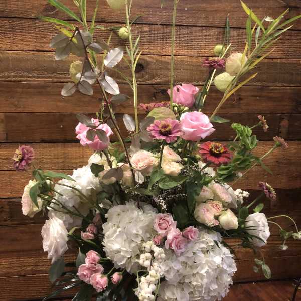 Tall floral arrangement with pink roses, white hydrangeas, and mixed blooms