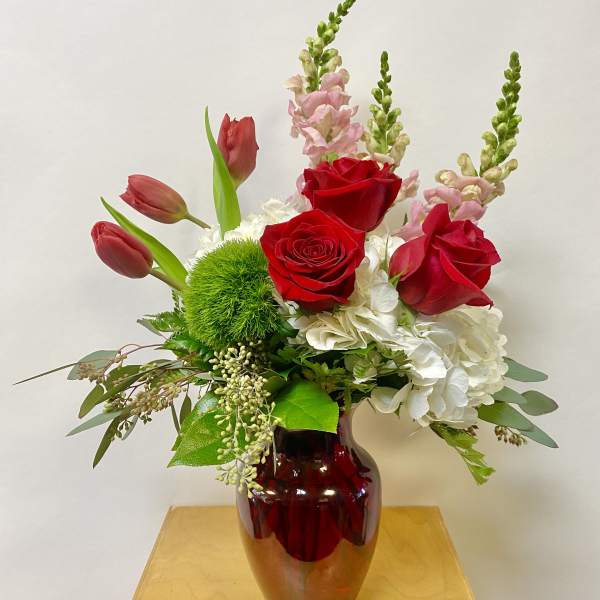 Red roses and pink tulips in a red glass vase