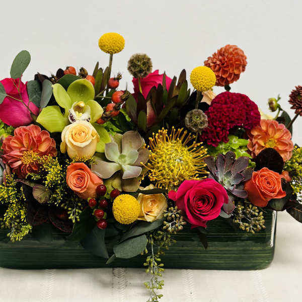 Colorful mixed flower arrangement in a rectangular green vase