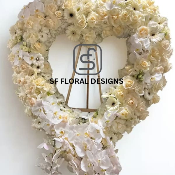 Large heart-shaped standing wreath of ivory roses, gerbera daisies, and orchids on a wooden easel