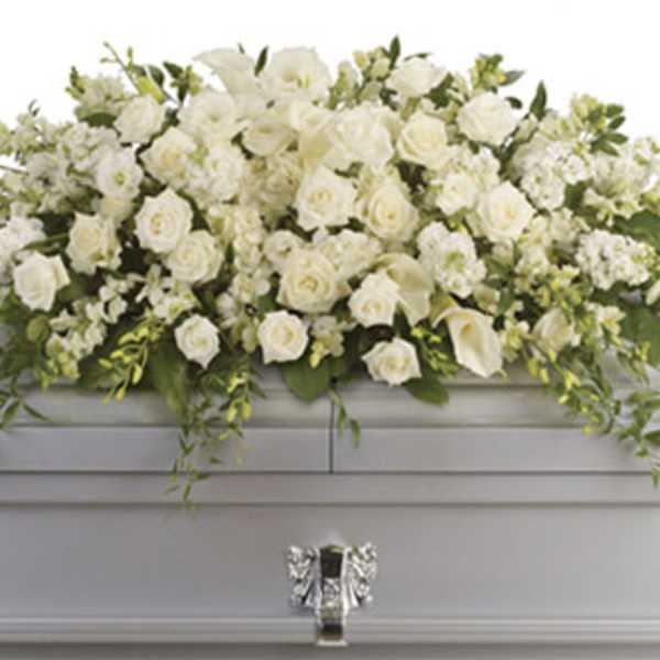 White rose and calla lily casket spray with cascading foliage on a silver casket