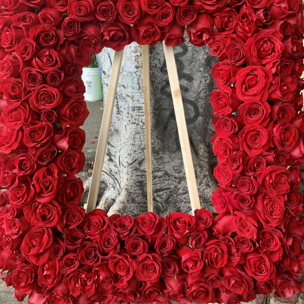 Large rectangular floral wreath of red roses on a wooden easel