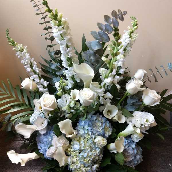 White roses, calla lilies, and blue hydrangeas in a large arrangement