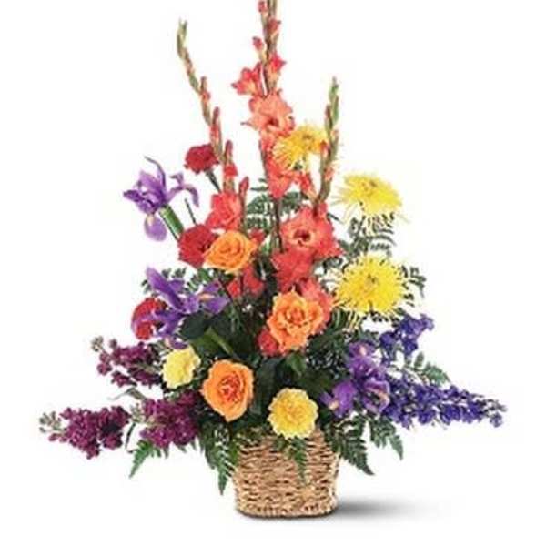Tall mixed arrangement of orange, yellow, and purple flowers in a woven basket