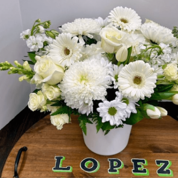 White flowers arranged in a white vase on a wooden tray