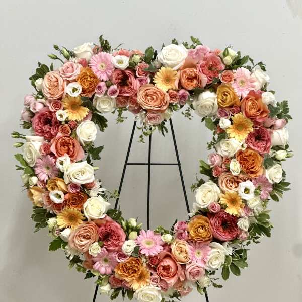 Heart-shaped floral wreath with pink, peach, white, and yellow blooms
