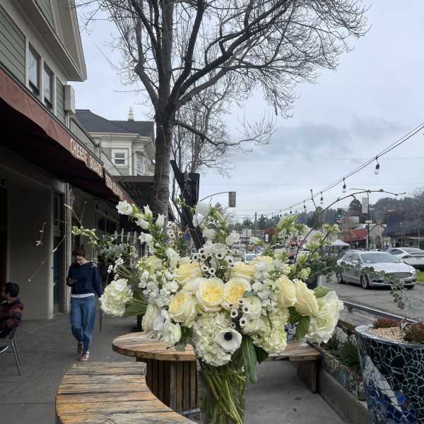Tall white floral arrangement in a clear glass vase