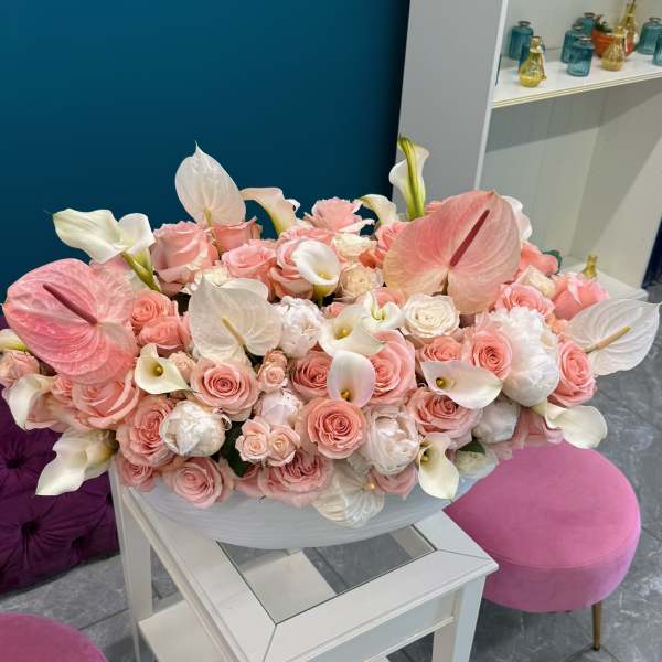 Large pastel bouquet of pink roses and white calla lilies in a white bowl
