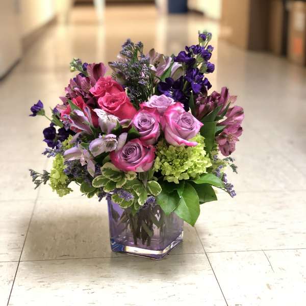Pink and purple rose bouquet in a square glass vase