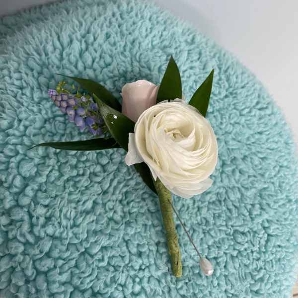 Small boutonniere with a white bloom and purple accent flowers