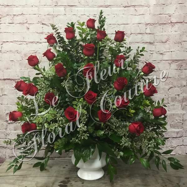Red roses arranged in a white pedestal vase