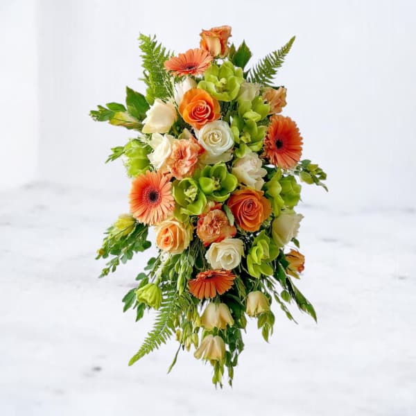 Cascading arrangement of orange, white, and green flowers with trailing greenery