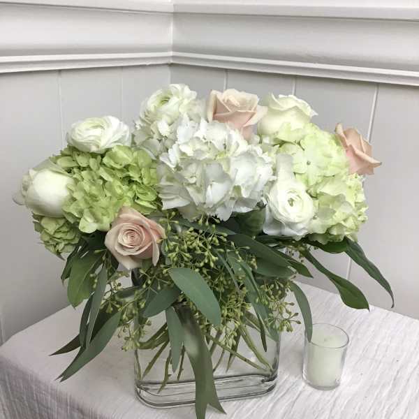 White and blush floral arrangement in a clear rectangular vase