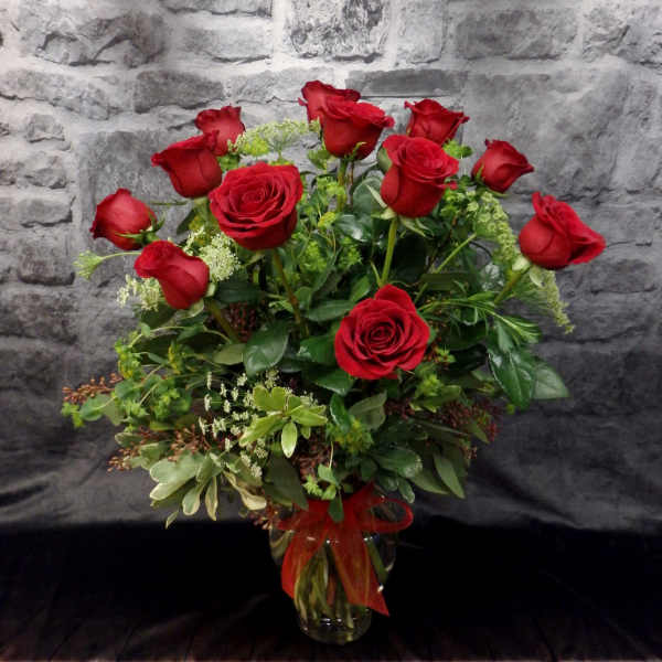 Red roses arranged in a clear glass vase with a red ribbon