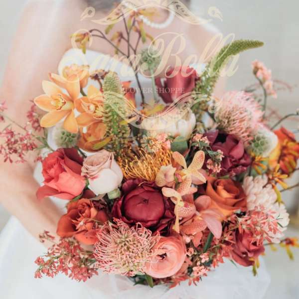 Handheld bouquet of orange, pink, and burgundy flowers