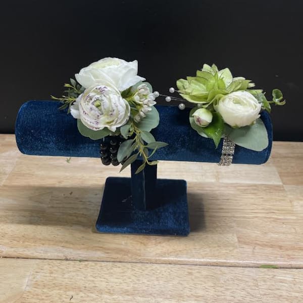 Two white floral corsages on a blue velvet stand