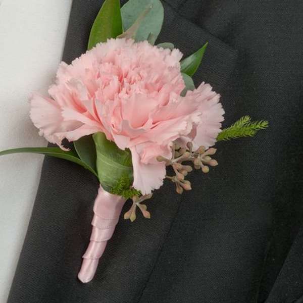 Pink carnation boutonniere with greenery on a black suit lapel