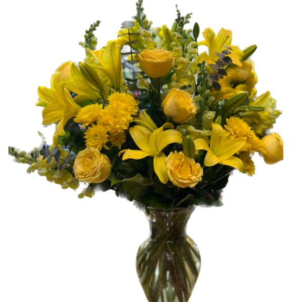 Yellow lilies and roses arranged in a clear glass vase