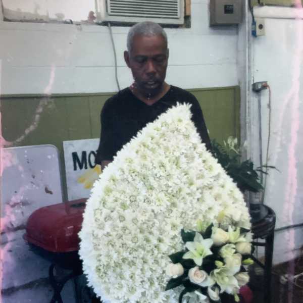 Large white funeral wreath on a stand with a small bouquet of pale flowers
