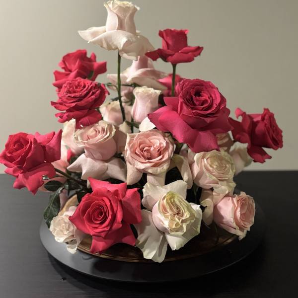 Arrangement of pink and red roses in a low round container