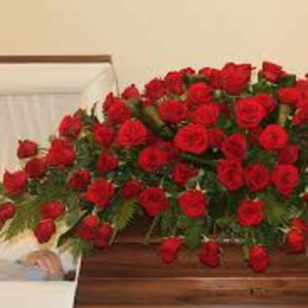 Large casket spray of red roses on a wooden casket