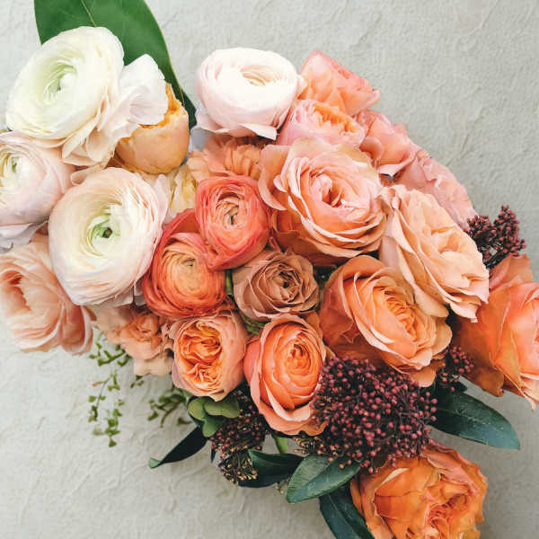 Peach and white ranunculus bouquet with dark berries