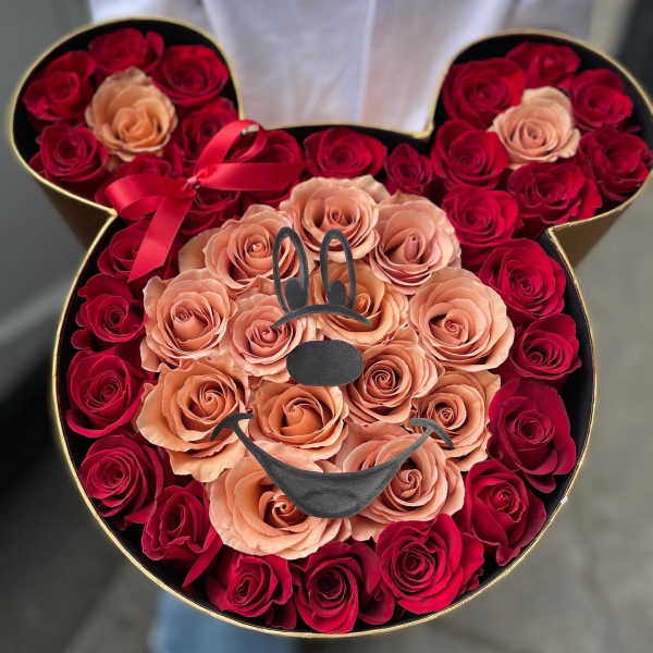Heart-shaped box filled with red and peach roses, with a ribbon bow and bunny face decoration