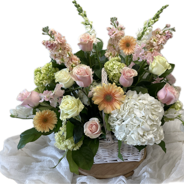 Pastel roses, gerbera daisies, and hydrangeas in a white basket