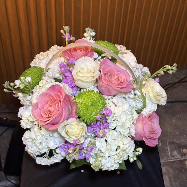 Basket arrangement of pink and white roses with white hydrangeas and green mums
