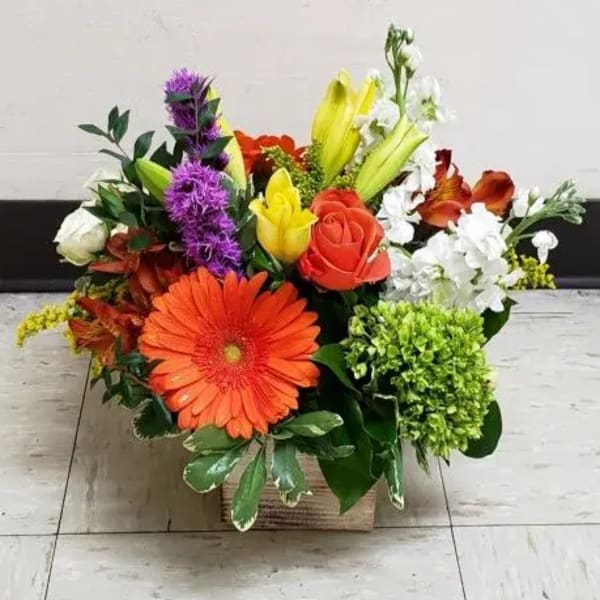 Mixed bouquet in a square box with orange, red, yellow, white, and purple flowers