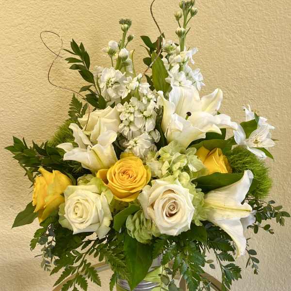 Yellow and white floral arrangement in a silver vase