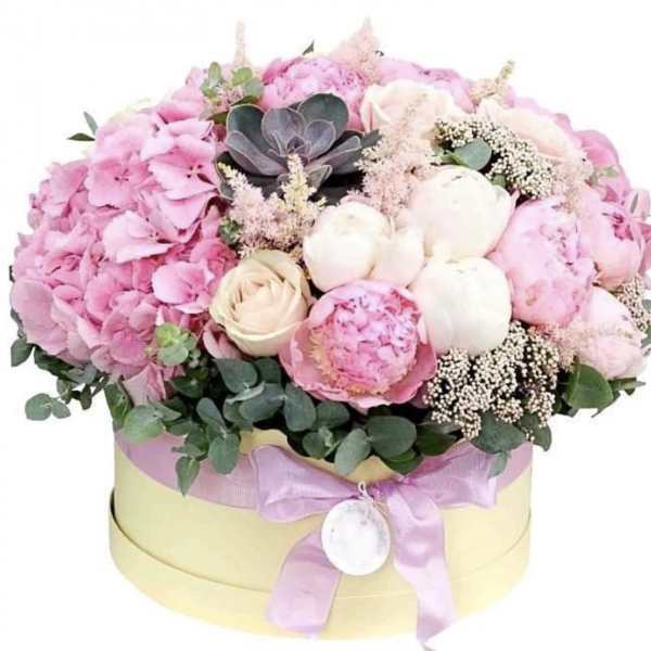 Pink and white floral arrangement in a round hat box with a ribbon