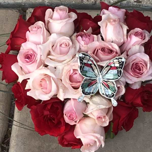Heart-shaped bouquet of pink and red roses with a butterfly ornament