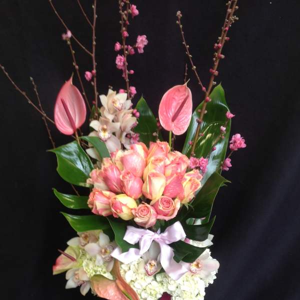 Tall bouquet of pink and white flowers with a ribbon-wrapped vase