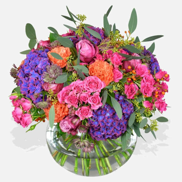 Bouquet of pink roses and purple hydrangeas in a clear glass vase