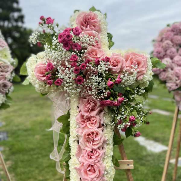 Large cross-shaped floral arrangement with pink roses and white blooms