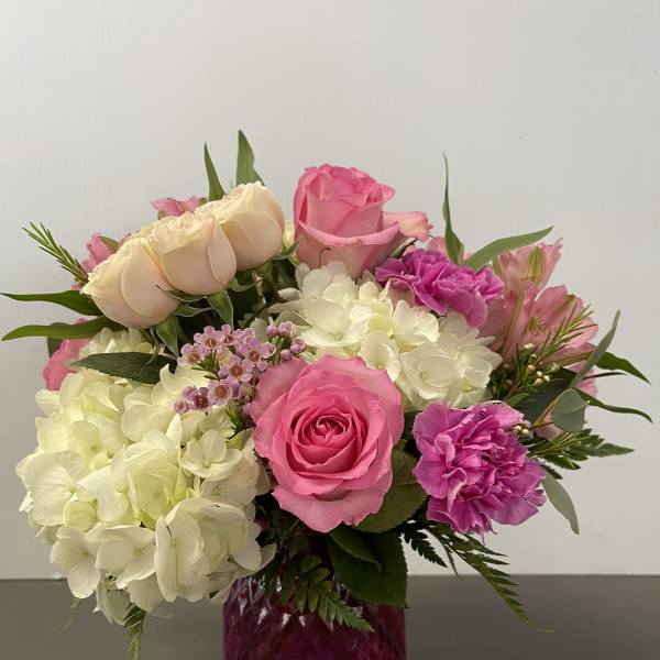 Pink and white flower arrangement in a magenta glass vase