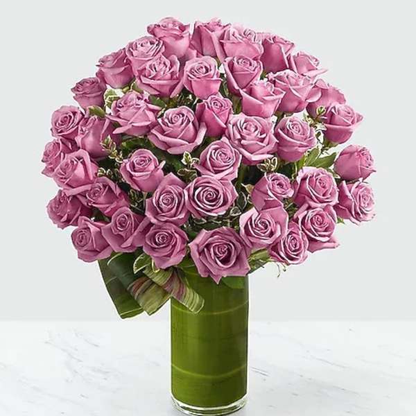 Pink roses arranged in a tall glass vase with a ribbon