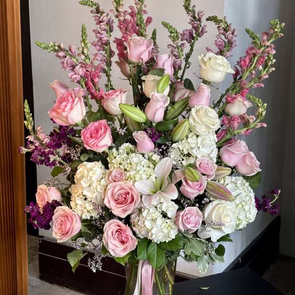 Large pink and white flower arrangement in a glass vase