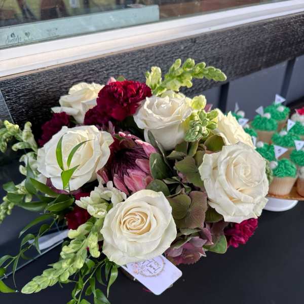 Bouquet of white roses with burgundy blooms and green accents