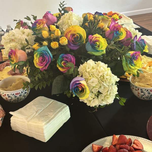 Rainbow roses and white hydrangeas arranged on a table.