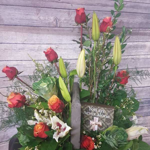Mixed bouquet with red roses, lilies, and a sympathy card