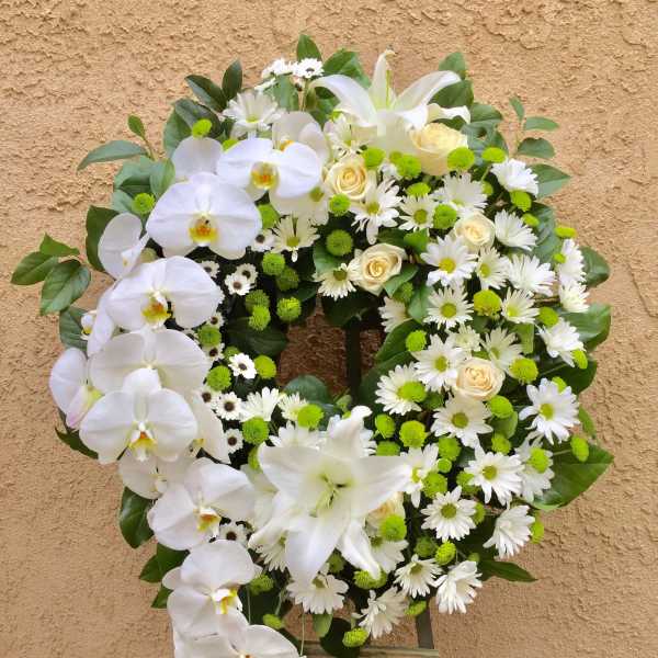 White floral wreath with orchids, daisies, roses, and green accents