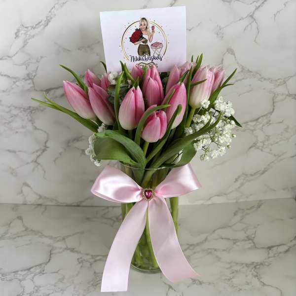Pink tulips in a glass vase with a pink ribbon