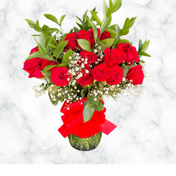 Red roses in a glass vase with baby's breath and a red ribbon